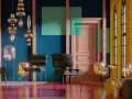 Nowoczesne wnętrze z designerskimi meblami i lampami, gdzie dominują ciepłe kolory: żółty, pomarańczowy i różowy, kontrastujące z granatową ścianą.