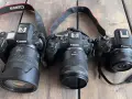 Trzy aparaty Canon EOS R, RP i R5 leżą obok siebie na drewnianym blacie. To **pełna klatka** sprzętu fotograficznego.